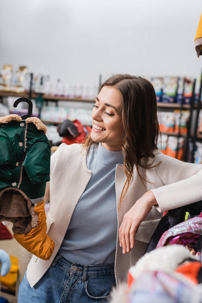 Веселая женщина смотрит на пиджак в магазине  - Фото, изображение