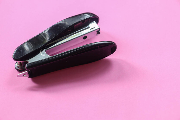 Изолированное изображение черного степлера для скрепки офисной бумаги на розовом фоне с местом для копирования текста. - Фото, изображение