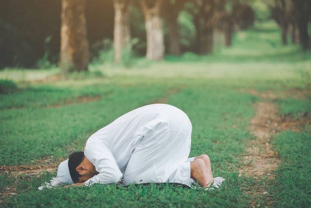 Religious muslim man  traditional kandura praying  outdoor at quiet nature  environment sun beams. - Zdjęcie, obraz