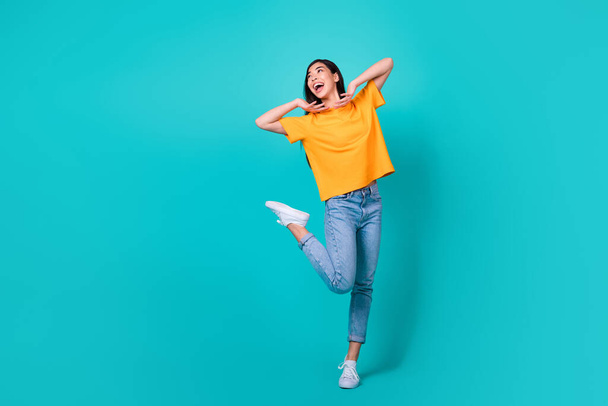 Full length photo of cool brunette lady dance look ad wear t-shirt jeans sneakers isolated on turquoise color background. - Foto, Imagem
