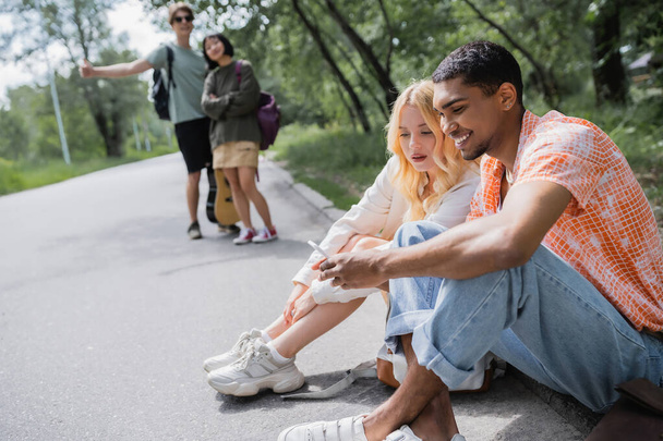 усміхнений афроамериканський чоловік шукає маршрут на смартфоні біля жінки та розмитих друзів
 - Фото, зображення