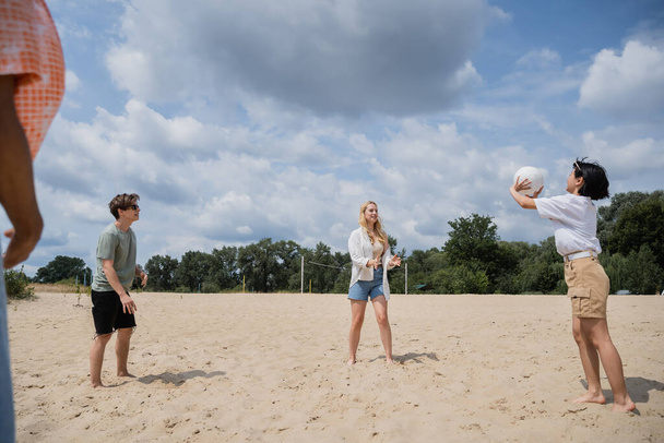 young multiethnic friends playing volleyball on sand beach in summer - 写真・画像