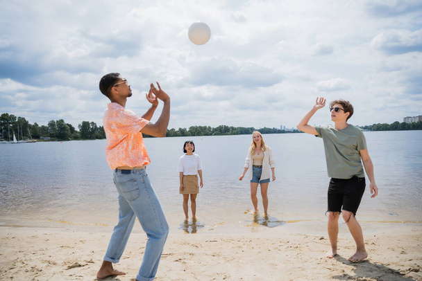 young multicultural friends playing beach volleyball near river - Valokuva, kuva