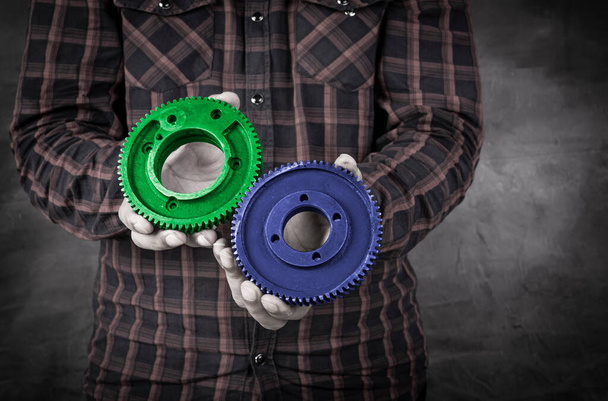 Professional holding two gears in blue and green color - solution concept. - Foto, imagen