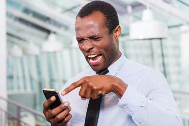 Frustrated African man with mobile phone - Φωτογραφία, εικόνα