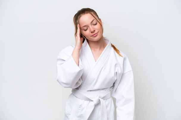Young caucasian girl doing karate isolated on white background with headache - 写真・画像
