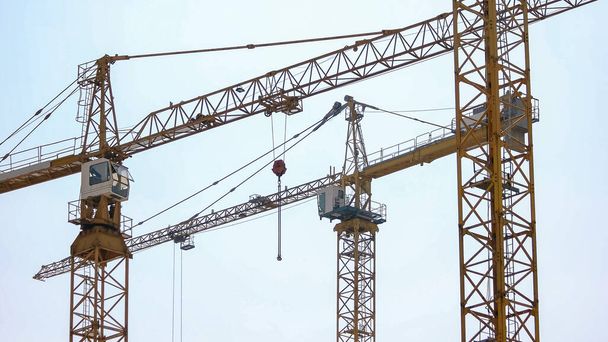 Three big yellow building crane on construction site. Morning sky background. - Fotó, kép