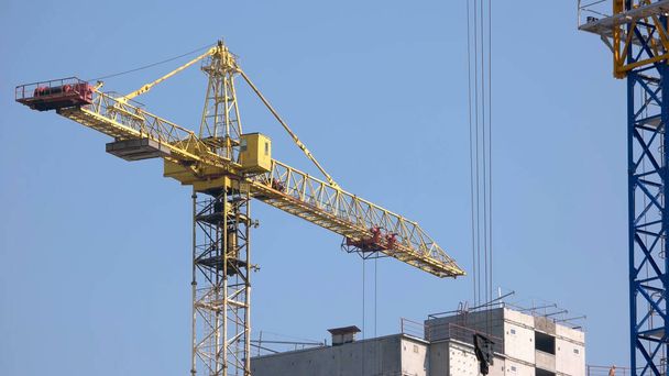 Yellow building crane on construction site. Side view of yellow crane. - Fotografie, Obrázek