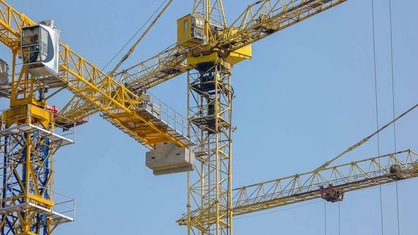 Steel yellow construction cranes over blue sky background. Moving construction crane. - Foto, imagen