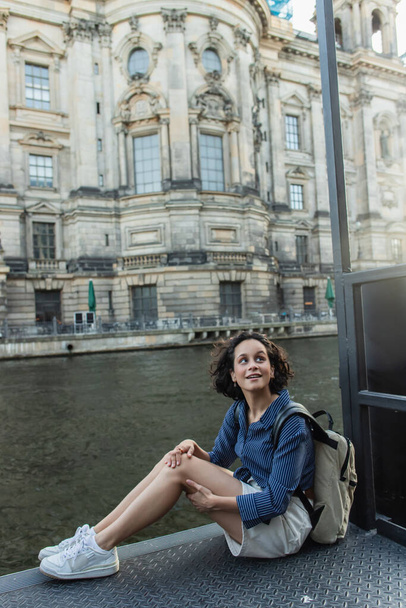 Здивований і молода жінка сидить біля річки і старовинний будинок у берліні.  - Фото, зображення