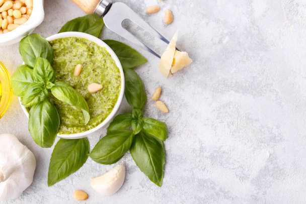 Pesto sauce and ingredients, cheese, basil, garlic, pine nuts, olive oil on grey stone background with copy space - Fotoğraf, Görsel