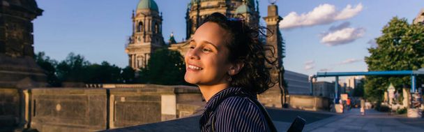 BERLIN, GERMANY - JULY 14, 2020: joyful young woman near blurred berlin cathedral, banner - Fotografie, Obrázek