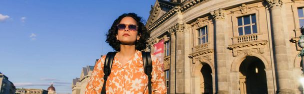 stylish young woman in sunglasses standing near building on museum island, banner - Foto, Bild