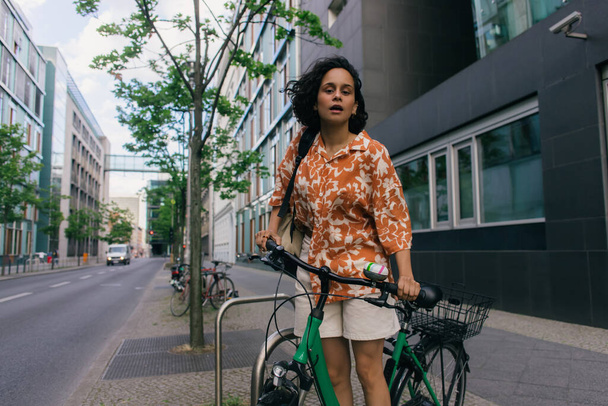 amazed young woman in summer outfit standing near bicycle in berlin  - Foto, Imagem