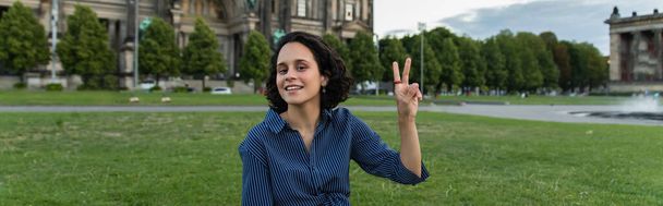 Ευτυχισμένη νεαρή γυναίκα με φορητό υπολογιστή που δείχνει την ειρήνη σημάδι στο Βερολίνο, πανό - Φωτογραφία, εικόνα