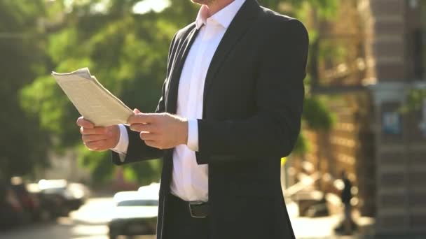 Бізнесмен в чорному костюмі читає газету або журнал на заході сонця в місті. Крупним планом руки
 - Кадри, відео