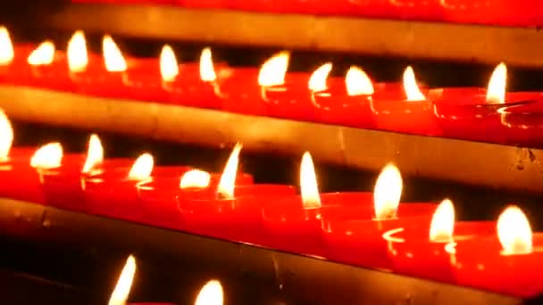 Row of lit burning red round candles in the cathedral. Religious candles for the rest of the soul in the catholic church. - Felvétel, videó