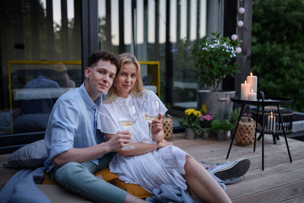A young couple clinking with wine outdoors, weekend away in tiny house in countryside, sustainable living. - Foto, Bild