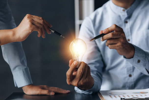 Businessman holds a glowing lamp, Creative new idea. Innovation, brainstorming, strategizing to make the business grow and be profitable. Concept execution, strategy planning and profit management. - 写真・画像