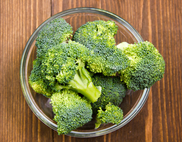 Broccoli inside bowl on wood from above - Valokuva, kuva