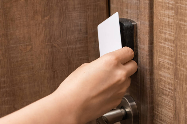 Woman hand puts key card to panel opening hotel room door.  - Foto, Imagem
