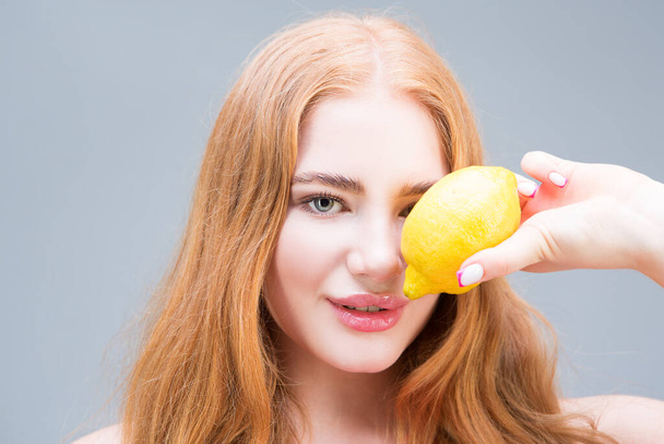 Молода красива жінка тримає лимон ізольовано на сірому фоні. Здорове харчування концепції. дієта
. - Фото, зображення