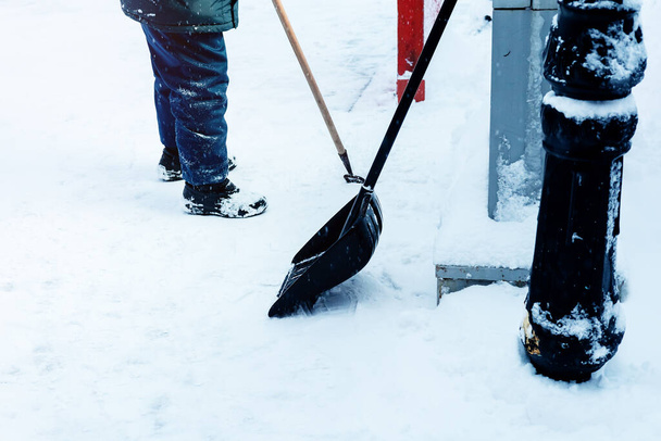 Ein Hausmeister beseitigt Schnee mit einer Schaufel - Foto, Bild