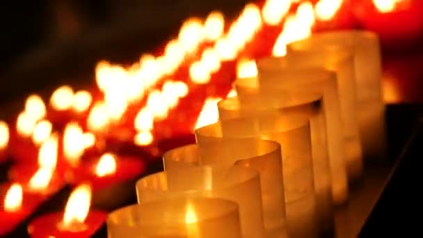 Row of lit burning red round candles in the cathedral. Religious candles for the rest of the soul in the catholic church. - Felvétel, videó