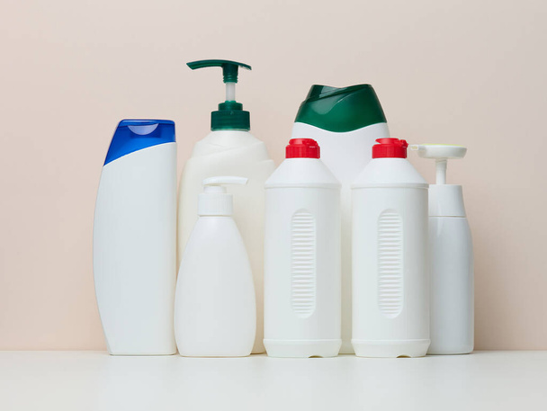 Various white plastic bottles for cosmetics, liquid soap, gel and shampoo on a beige background - Valokuva, kuva