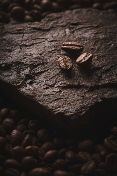 Roasted coffee beans on stone pedestal brown background - Фото, изображение