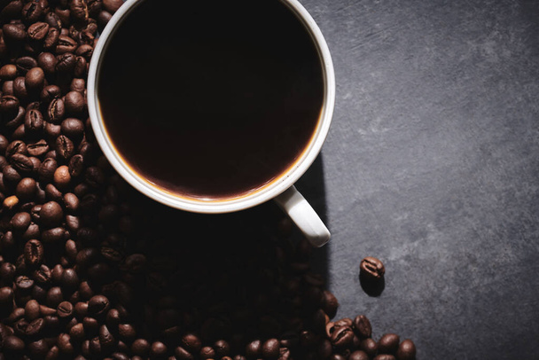 White cup of freshly brewed roasted coffee beans on gray background - 写真・画像