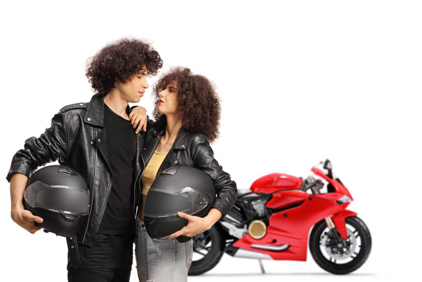 Young couple with a motorbike in leather jackets holding helmets isolated on white background - Φωτογραφία, εικόνα