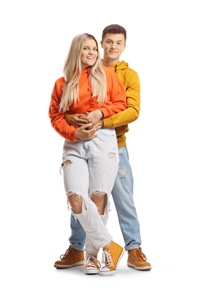 Teenage couple in embrace looking at camera isolated on white background - 写真・画像