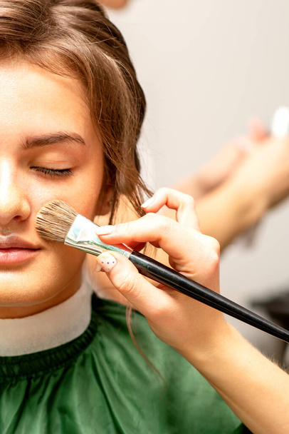 The makeup artist applies a cosmetic tonal foundation on the face using a makeup brush - Fotó, kép