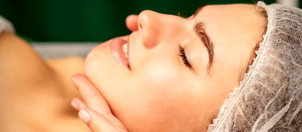 Masaż twarzy. Ręce masażystki masującej szyję młodej białej kobiety w salonie spa, koncepcja masażu zdrowotnego - Zdjęcie, obraz