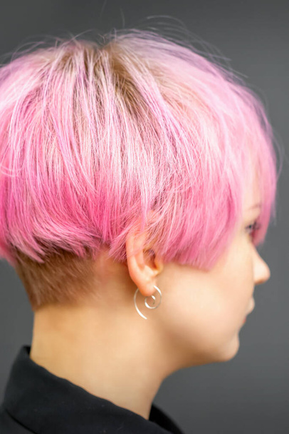 Profile of a beautiful young caucasian woman with short bob pink hairstyle on dark gray background - Foto, imagen