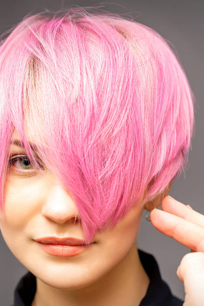 Coiffeur avec les mains et peigne est vérifier et fixer la coiffure rose courte de la jeune femme blanche dans un salon de coiffure - Photo, image