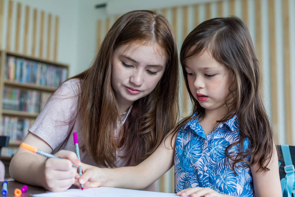 Girl is doing homework in the Classroom. Back to school! Cute industrious children are sitting at desks indoors. Kids are learning in class. - Zdjęcie, obraz