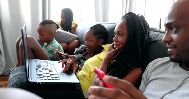 Afrykańska rodzina patrząc na laptopa i urządzeń komórkowych w domu sofa - Materiał filmowy, wideo