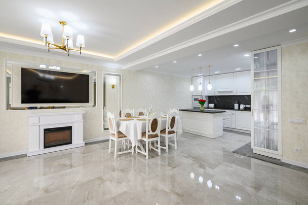 Luxury white large domestic kitchen with glossy marble floor, kitchen island and dining table - Foto, Imagen