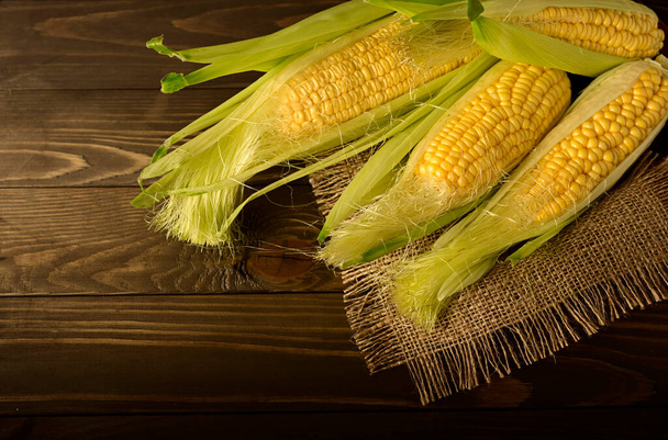 Corn cobs on rough fabric napkins on wooden table. - Foto, Imagem
