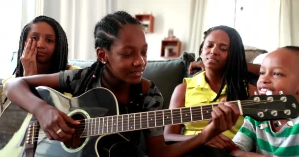 Sıradan siyahi Afrikalı aile gitarla bağ kuruyor. Kızım müzik aleti çalıyor.  - Video, Çekim