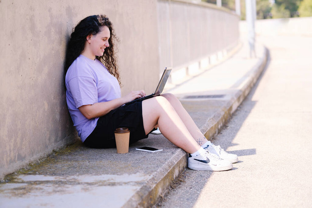 Brunette girl with curly hair working in the middle of nature with the laptop. - 写真・画像