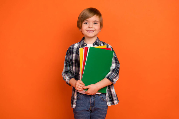 Photo of young cheerful school boy hold hands materials clever isolated over orange color background. - Valokuva, kuva