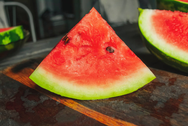 Sweet watermelon with pits on a wooden table. A triangular slice of watermelon on a wooden table. beautiful slice of watermelon. - Valokuva, kuva