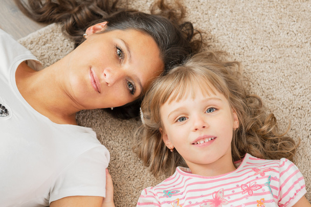 Madre e figlioletta sdraiati insieme sul pavimento
 - Foto, immagini