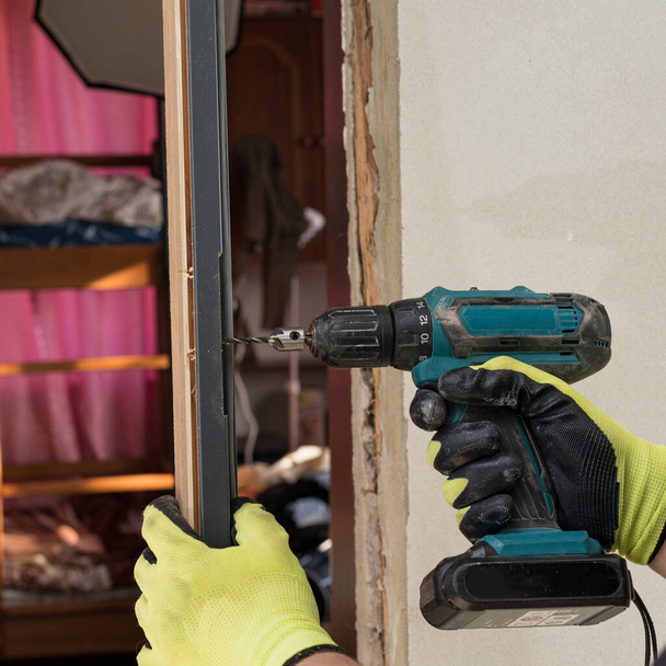 In the door frame, the master drills a hole for further attachment to the wall, installation of the door. - Foto, Imagem