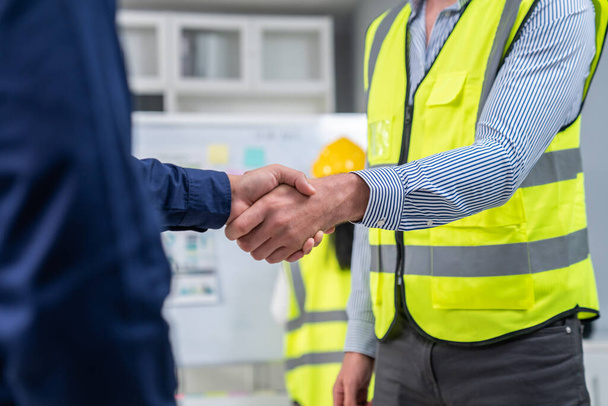 After concluding the meeting, competent investor shakes hands with engineer. Concept of the agreement between engineers and investors. - Photo, image