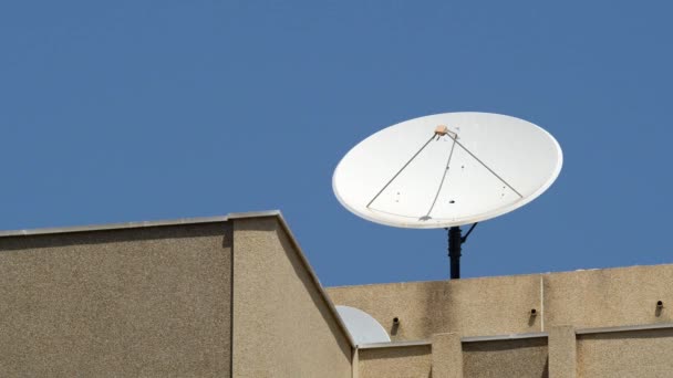 Большая спутниковая тарелка на крыше дома против чистого голубого неба. Прием ТВ сигнала - Кадры, видео