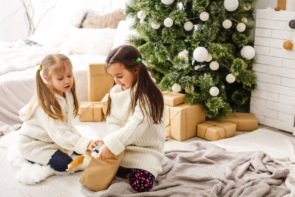 dwie małe dziewczynki Dzielenie się niespodzianką na Boże Narodzenie rano. - Zdjęcie, obraz